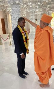 Prime Minister Dr. Terrance Drew while receiving blessings from Brahmavihari Swami 